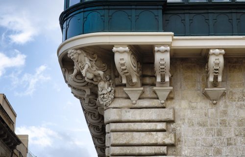 Detail of an old urban building stone facade with tall windows and decorative elements